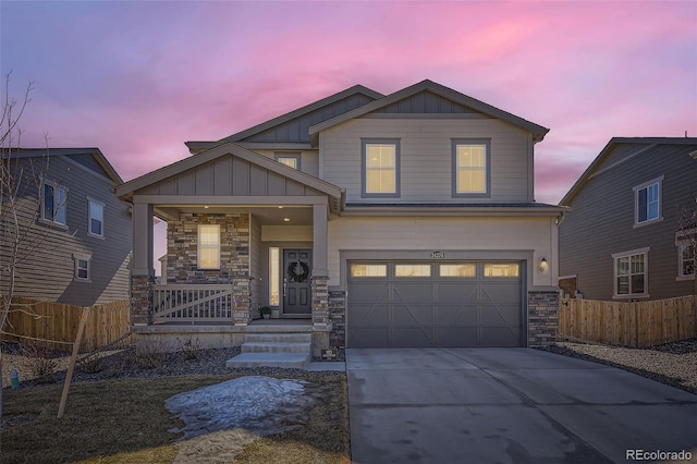 view of front of home featuring concrete driveway, stone siding, covered porch, fence, and board and batten siding