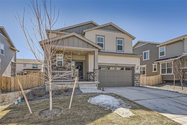 view of front facade featuring concrete driveway, stone siding, covered porch, fence, and board and batten siding