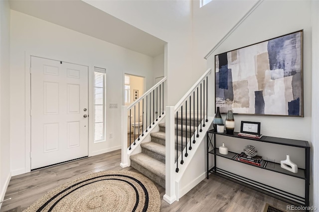 foyer with stairs, baseboards, and wood finished floors