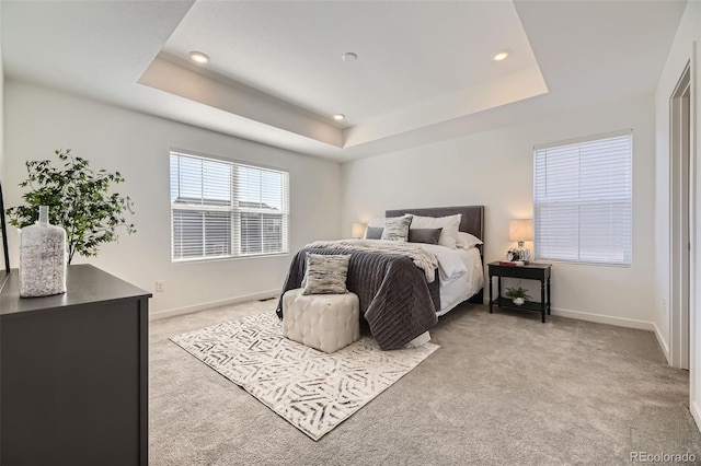 bedroom featuring light carpet, baseboards, and a raised ceiling