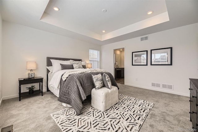 bedroom featuring a raised ceiling, visible vents, and baseboards