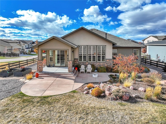 rear view of property featuring stone siding, a patio area, stucco siding, and fence