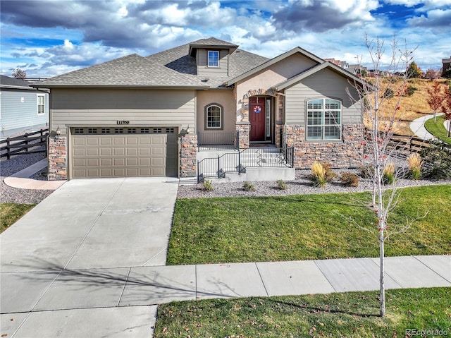 view of front of house featuring fence, stone siding, concrete driveway, a garage, and a front lawn
