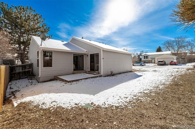 snow covered rear of property featuring a patio