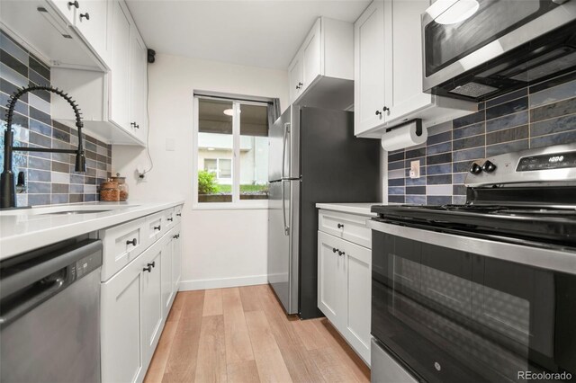 4068 S Atchison Way Unit 103, Aurora, CO 80014 - kitchen featuring stainless steel appliances, a sink, light wood finished floors, decorative backsplash, and white cabinets