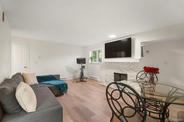 4068 S Atchison Way Unit 103, Aurora, CO 80014 - living room featuring a baseboard heating unit, light wood-style flooring, a brick fireplace, and baseboards