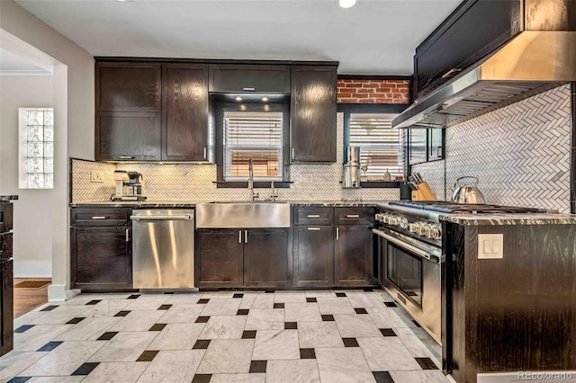 kitchen featuring a sink, dark brown cabinets, ventilation hood, appliances with stainless steel finishes, and dark countertops