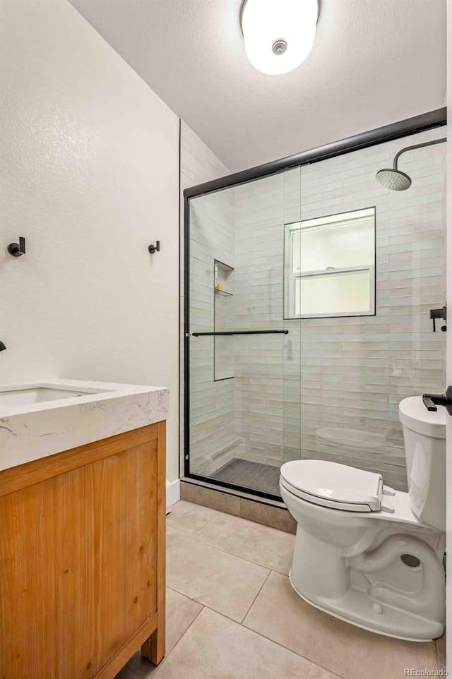 bathroom featuring walk in shower, vanity, tile patterned floors, and toilet