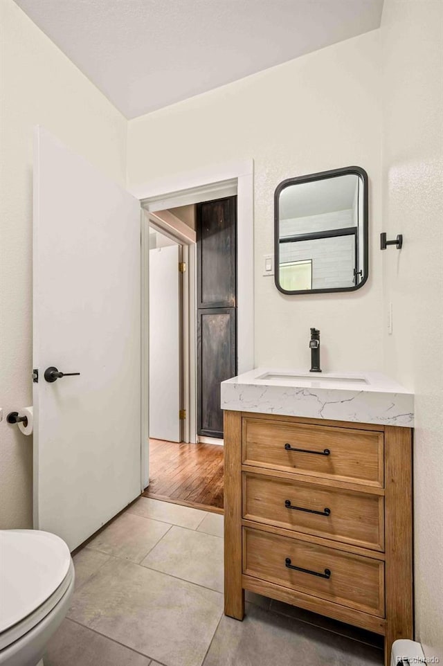 half bathroom featuring toilet, tile patterned floors, and vanity