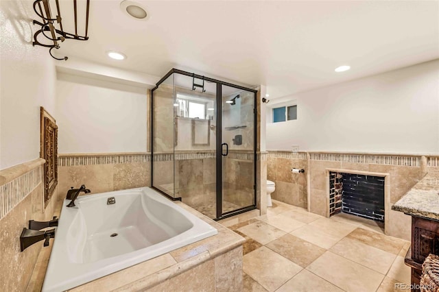 full bathroom featuring shower with separate bathtub, a fireplace, tile walls, vanity, and toilet