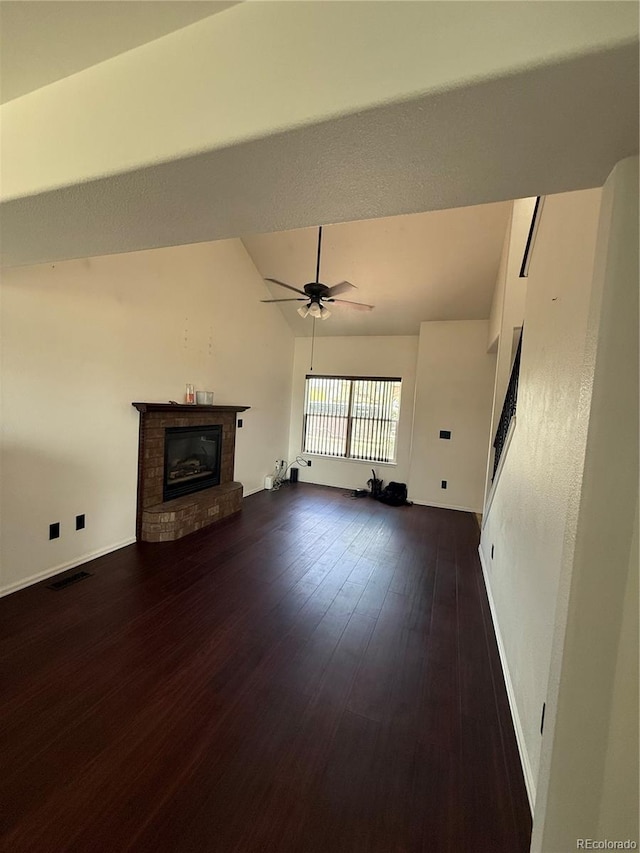 8318 Ivory Loop, Peyton, CO 80831 - unfurnished living room featuring a fireplace, vaulted ceiling, baseboards, dark wood-type flooring, and a ceiling fan