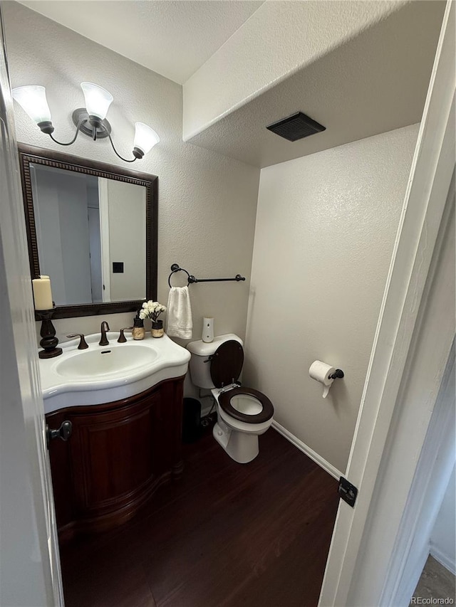 8318 Ivory Loop, Peyton, CO 80831 - bathroom featuring toilet, vanity, wood finished floors, baseboards, and a textured wall