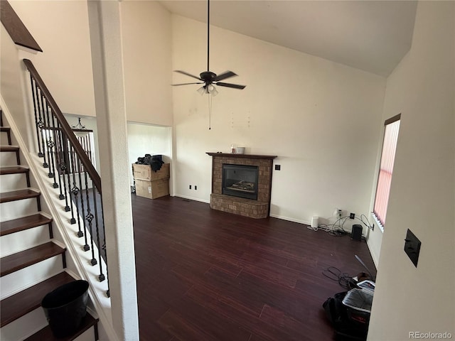 8318 Ivory Loop, Peyton, CO 80831 - unfurnished living room with high vaulted ceiling, a brick fireplace, wood finished floors, stairway, and ceiling fan