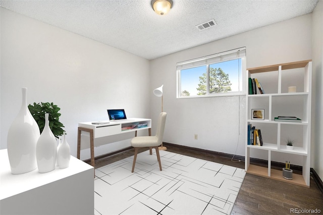 office featuring baseboards, visible vents, a textured ceiling, and wood finished floors