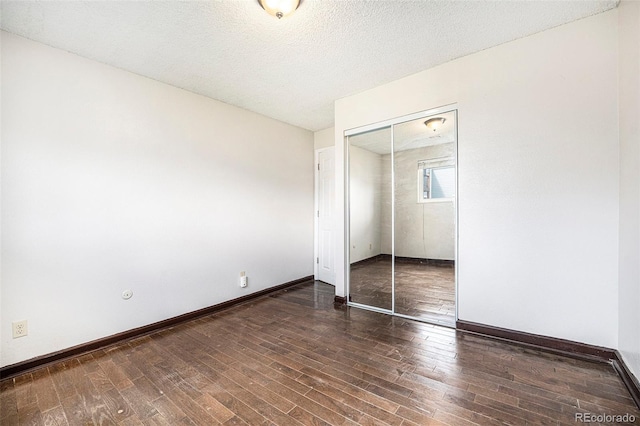 unfurnished bedroom with baseboards, a closet, a textured ceiling, and wood finished floors