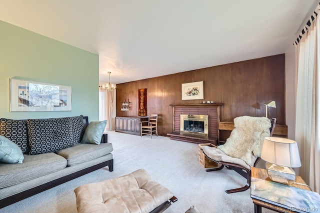 living area featuring wooden walls, a fireplace, carpet, and an inviting chandelier