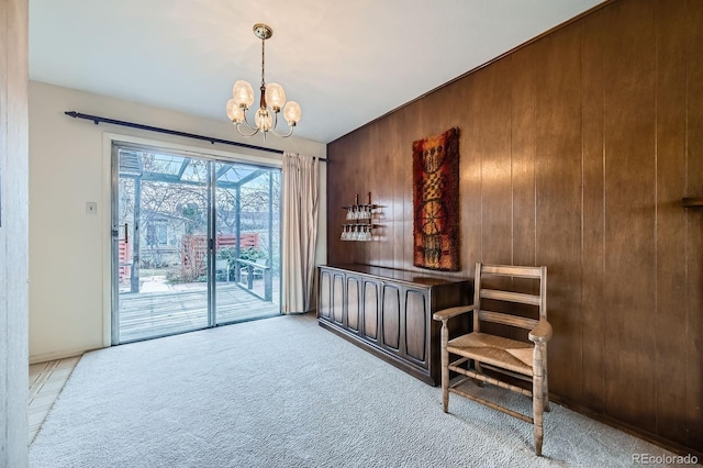 living area featuring carpet, a chandelier, and wood walls