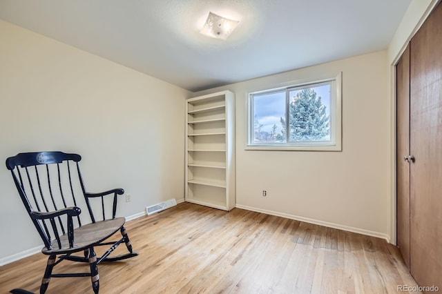 sitting room with visible vents, baseboards, and light wood-style flooring