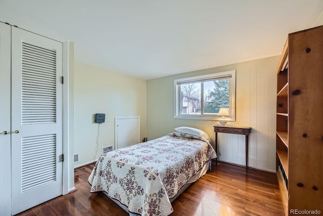 bedroom with dark wood-style floors, visible vents, and a closet