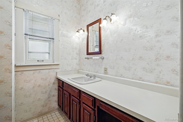 bathroom featuring vanity, wallpapered walls, and baseboards