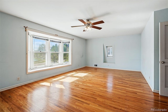 spare room featuring wood finished floors, a ceiling fan, and baseboards