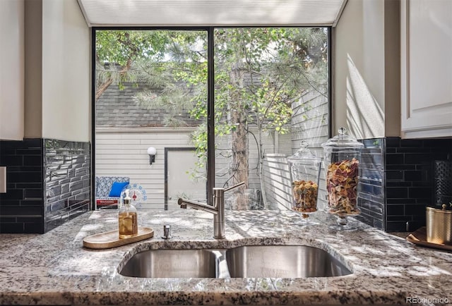 345 Harrison St, Denver, CO 80206 - kitchen view of a sink, tasteful backsplash, light stone countertops, and white cabinets