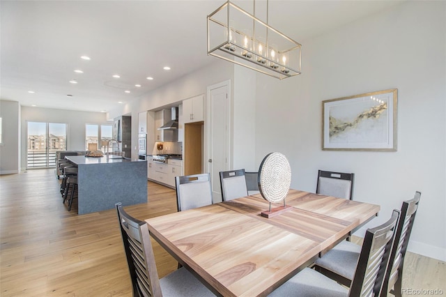 dining space with a chandelier, sink, and light hardwood / wood-style flooring