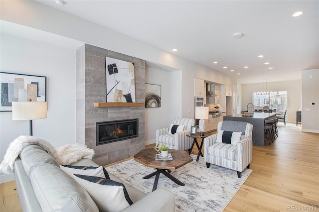 living room with sink, a tile fireplace, light wood-type flooring, and tile walls