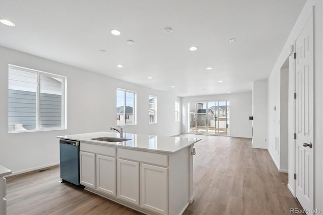 kitchen featuring sink, light hardwood / wood-style flooring, stainless steel dishwasher, an island with sink, and white cabinetry