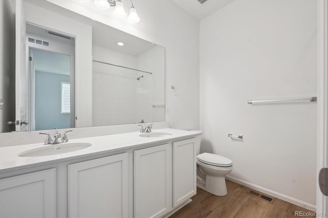 bathroom with a shower, wood-type flooring, vanity, and toilet