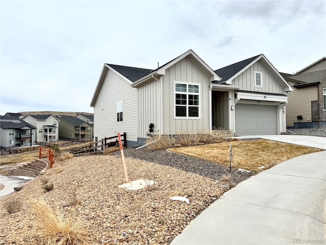 view of front facade featuring board and batten siding, a shingled roof, fence, concrete driveway, and an attached garage