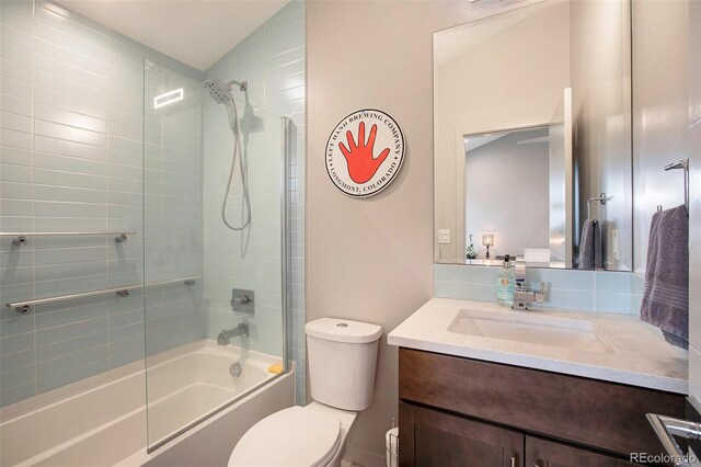 full bathroom featuring vanity, tiled shower / bath combo, lofted ceiling, and toilet