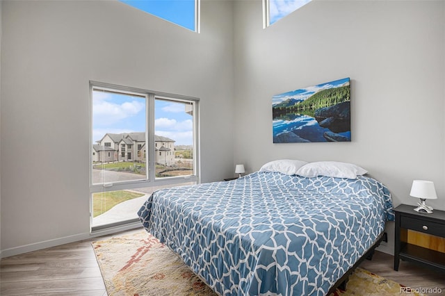 bedroom featuring wood-type flooring and a high ceiling