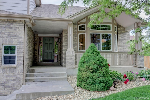 14910 Williams St, Thornton, CO 80602 - doorway to property featuring covered porch, stone siding, and roof with shingles