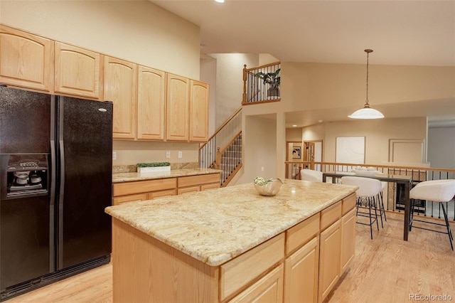 14910 Williams St, Thornton, CO 80602 - kitchen featuring black refrigerator with ice dispenser, light brown cabinets, light wood finished floors, hanging light fixtures, and light stone counters
