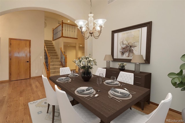 14910 Williams St, Thornton, CO 80602 - dining area featuring light wood-type flooring, arched walkways, a chandelier, stairs, and a high ceiling