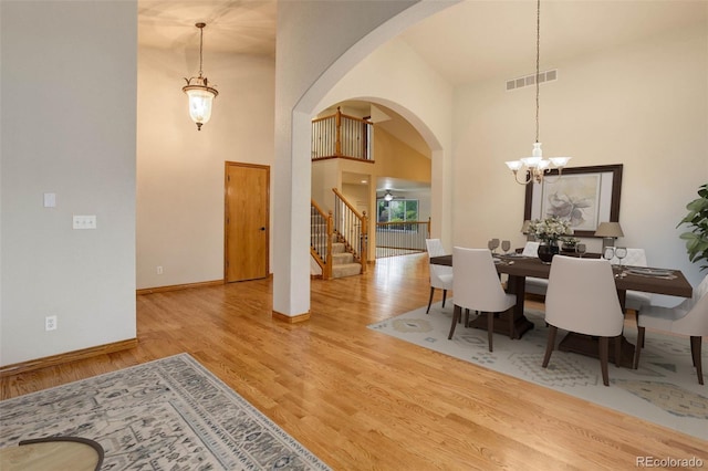 14910 Williams St, Thornton, CO 80602 - dining area with stairs, arched walkways, wood finished floors, a chandelier, and a high ceiling