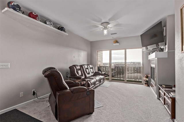 living area featuring carpet, visible vents, baseboards, and ceiling fan