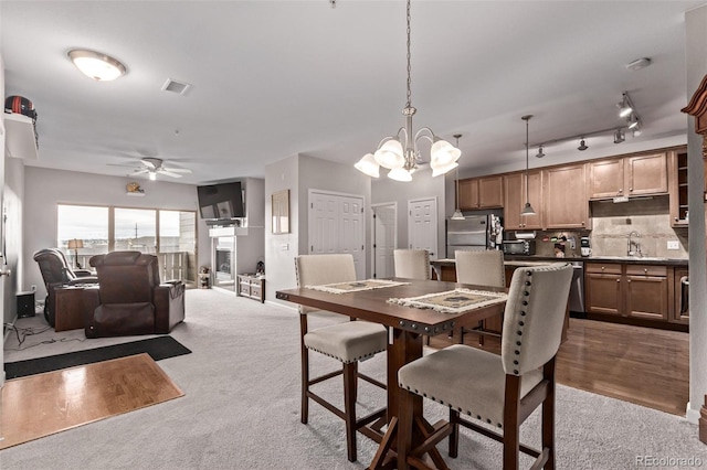 dining room with carpet floors, ceiling fan with notable chandelier, and visible vents