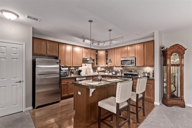 kitchen featuring a center island, a breakfast bar, visible vents, dark countertops, and stainless steel appliances