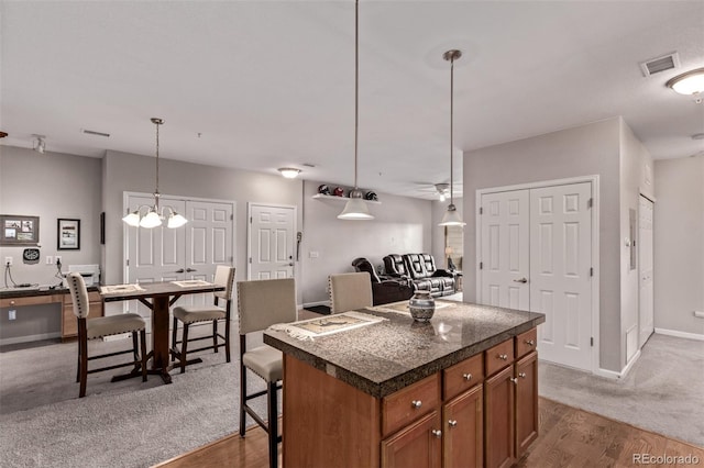kitchen with a center island, baseboards, visible vents, wood finished floors, and brown cabinets