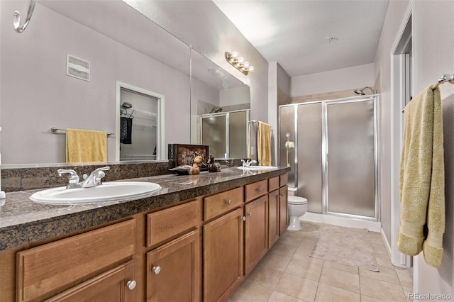 bathroom featuring a stall shower, tile patterned flooring, toilet, and a sink