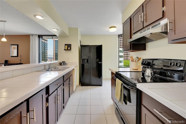 kitchen with decorative light fixtures, black appliances, tile counters, and sink