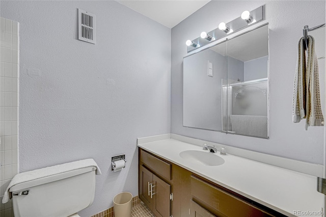 bathroom featuring toilet, walk in shower, and vanity