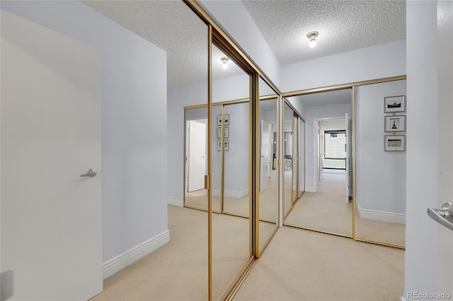 hallway with a textured ceiling and light colored carpet