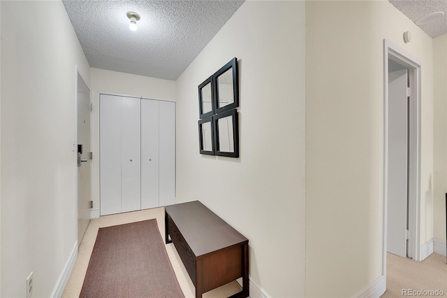 hall featuring a textured ceiling and light colored carpet