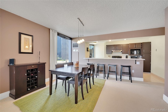 dining space with a textured ceiling and light carpet