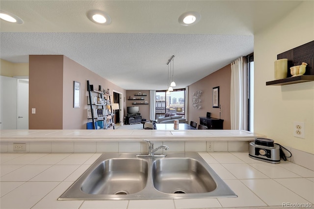 kitchen with sink, tile counters, and a textured ceiling