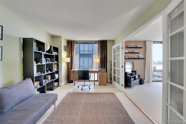 carpeted office space featuring a textured ceiling, french doors, and expansive windows