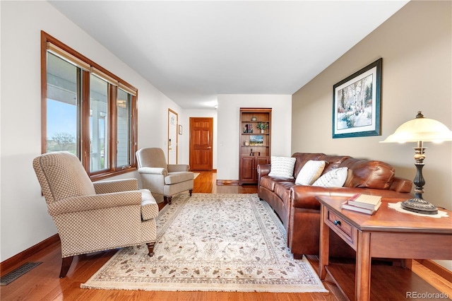 living room featuring baseboards, wood finished floors, and visible vents